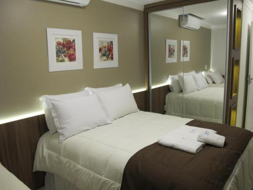 a hotel room with two beds and a mirror at Temporada Gramado e Canela- Apartamento Centro Catedral in Canela