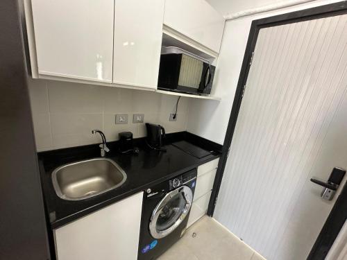 a small kitchen with a sink and a washing machine at North coast Cozy cabin Seaview & Lagon in D-bay I Beach Access Included in Zāwiyat ‘Abd al Mun‘im