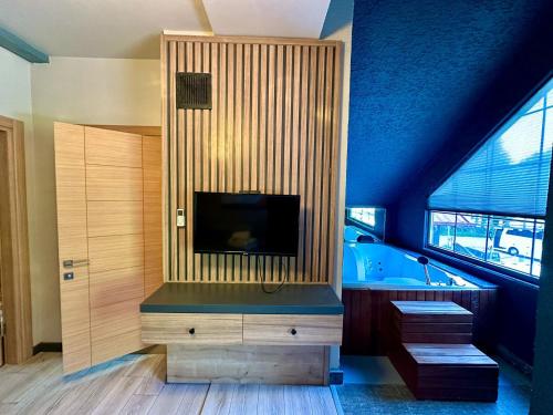 a bathroom with a tub and a television in a room at Uzungöl Bungalow in Uzungol