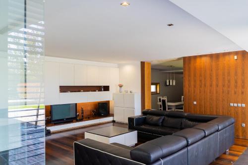 a living room with a black leather couch and a kitchen at Exclusive Villa & SPA - by Proguest in Vila Verde