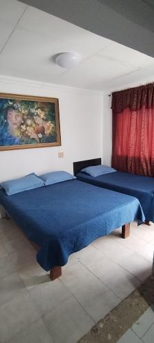 a bedroom with two beds and a painting on the wall at Hostal Poseidon del Mar in San Andrés
