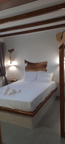 a bedroom with a white bed with a wooden headboard at Siroccos Apartment in Vlychádia