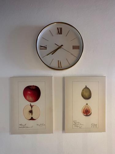 two pictures of an apple and a clock on a wall at Nannerls Penthouse in Sankt Gilgen