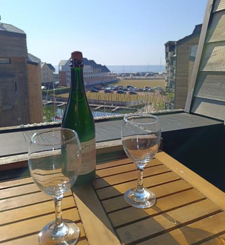 2 verres à vin assis sur une table avec une bouteille de vin dans l'établissement Studio neuf vue mer Marina Deauville, à Deauville