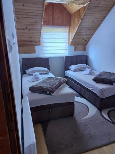 two beds in a small room with wooden ceilings at Vikendica u srcu Bjelasnice in Trnovo