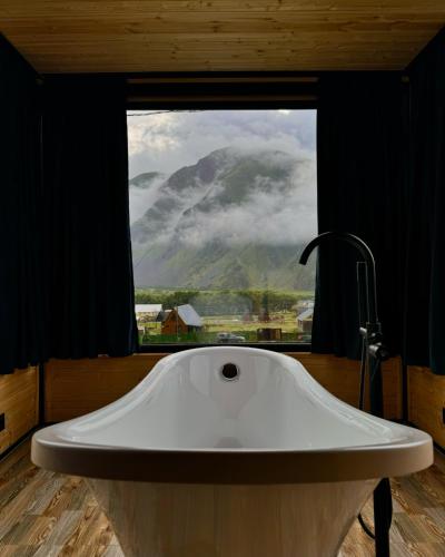 a large white tub in a bathroom with a window at Kazbegi Inn Cottages in Stepantsminda