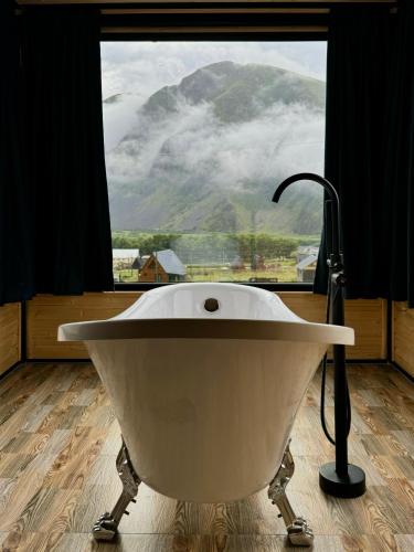 a bath tub in a bathroom with a view of a mountain at Kazbegi Inn Cottages in Stepantsminda