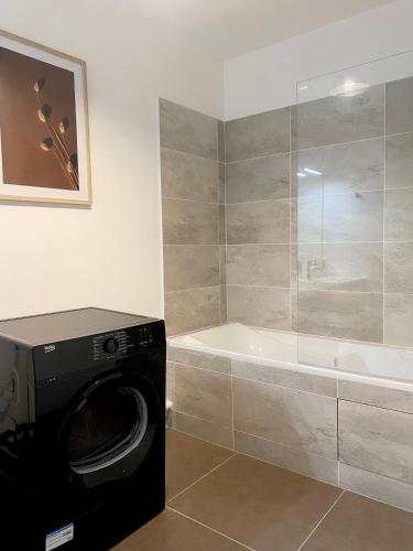 y baño con lavadora y bañera. en 3 pièces tout neuf de haut standing à 10mn de Paris avec terrasse vue Sacré Coeur, en Asnières-sur-Seine