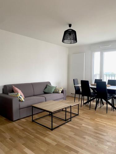 un salon avec un canapé, une table et des chaises dans l'établissement 3 pièces tout neuf de haut standing à 10mn de Paris avec terrasse vue Sacré Coeur, à Asnières-sur-Seine