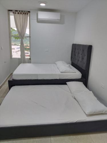 two beds sitting in a room with a window at apartaestudios luna azul rodadero in Gaira