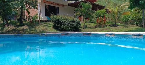 a large blue swimming pool in front of a house at Casa en el campo - villeta in Villeta