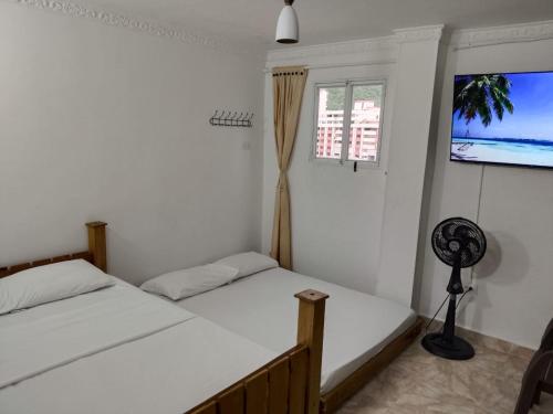 a bedroom with two beds and a flat screen tv at apartaestudios luna azul rodadero in Gaira