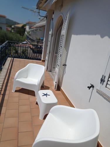 two white benches sitting on the side of a building at Alloggio panoramico sul mare di Vindicio in Formia
