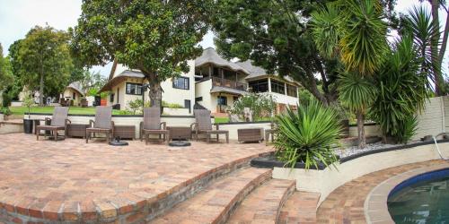 a house with a patio with chairs and a swimming pool at Winelands Villa Guesthouse and Cottages in Somerset West