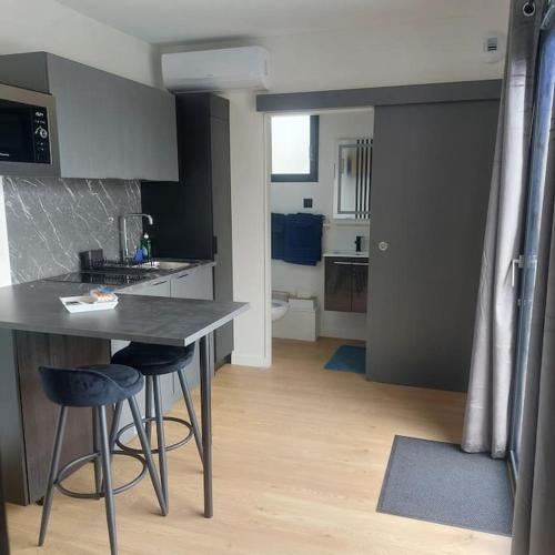 une cuisine avec une table et deux tabourets de bar dans l'établissement Studio privatif indépendant, à Saint-Thurial