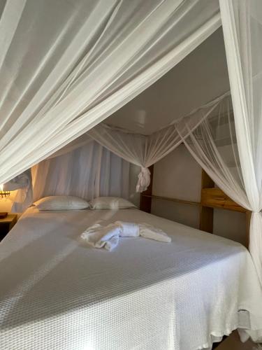 a bedroom with a white bed with a canopy at Residencial Lima in Trancoso