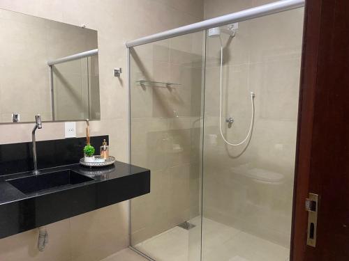a bathroom with a glass shower and a sink at Ribeiro Flat in Araxá