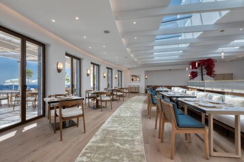 a dining room with tables and chairs and windows at Sandblu Resort in Kamari