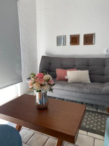 a living room with a couch and a table with flowers at Depa BN 06 in Barra de Navidad