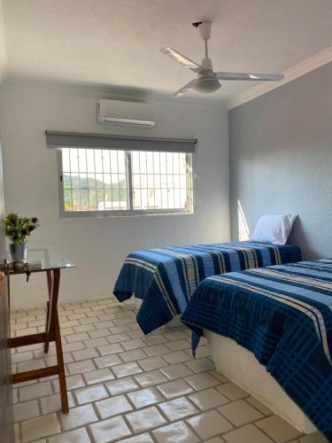 a bedroom with two beds and a table and a window at Depa BN 06 in Barra de Navidad