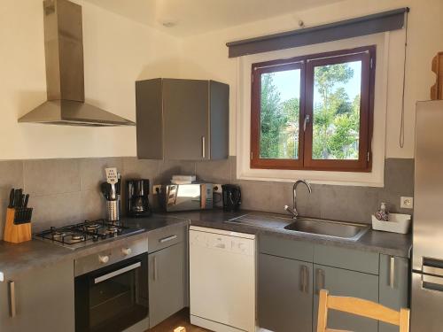 une cuisine avec un évier, une cuisinière et une fenêtre dans l'établissement Gite du Champ de l'épine, à Périers-en-Auge