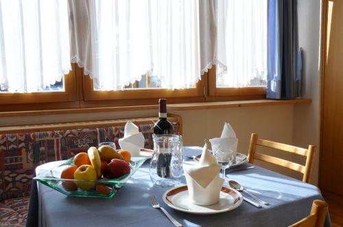 a table with a bowl of fruit and a bottle of wine at Residence Vajolet San Cassiano in San Cassiano