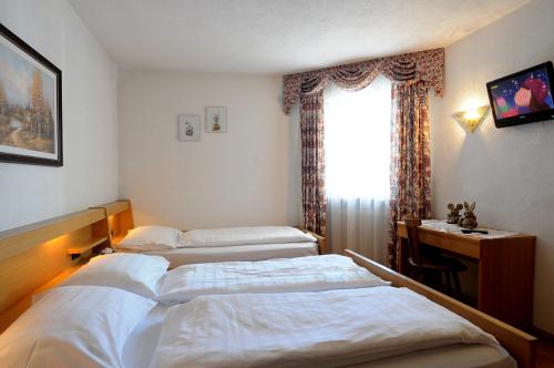 a hotel room with two beds and a window at Residence Vajolet San Cassiano in San Cassiano