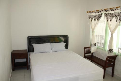 een slaapkamer met een wit bed en een raam bij Jasmine Heritage Homestay in Yogyakarta