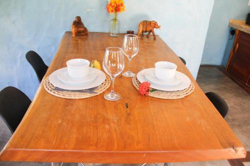 a wooden table with two glasses and plates and aeder at Casa Maresia Ilha do Guajiru in Itarema