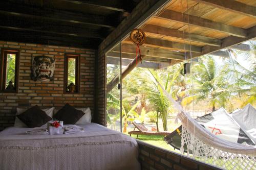 a bedroom with a hammock and a large window at Casa Maresia Ilha do Guajiru in Itarema