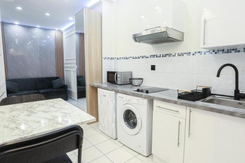 een keuken met een spoelbak en een wasmachine bij Appartement Royal carré d'or de Paris 17 eme in Parijs