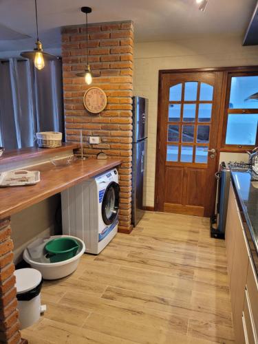 a kitchen with a washing machine and a brick wall at Casa en calle Mondello, Piriápolis in Piriápolis