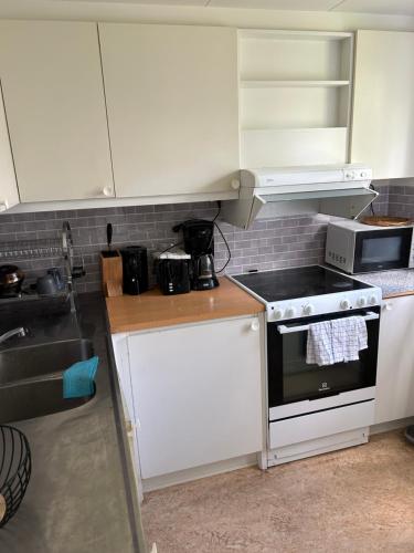 a kitchen with white cabinets and a stove top oven at Uteplats in Gothenburg