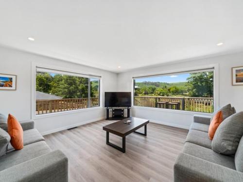 a living room with two couches and a flat screen tv at Fantail Haven in Kinloch