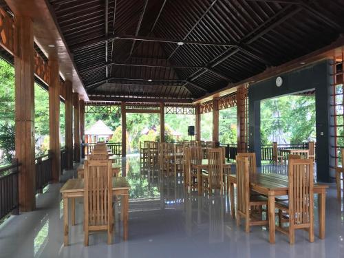 a restaurant with wooden tables and chairs and windows at Pohon Purba Resort & Restaurant in Labuan Lombok