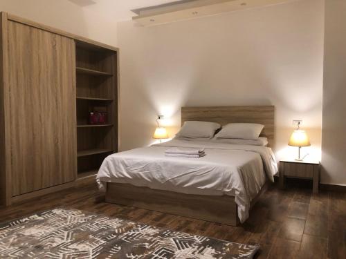 a bedroom with a large bed with two lamps and a rug at Apartments Next to Mivida in New cairo