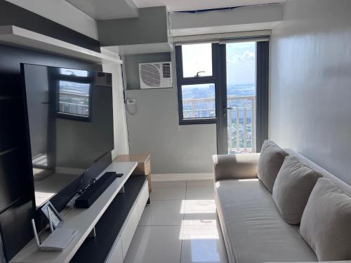 Una sala de estar con un sofá y un televisor. en 1 bedrm condo, Tower 2, Hor 101, en Cebú
