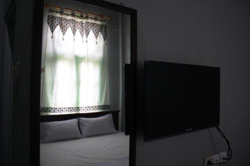 een slaapkamer met een raam met een bed en een flatscreen-tv bij Jasmine Heritage Homestay in Yogyakarta