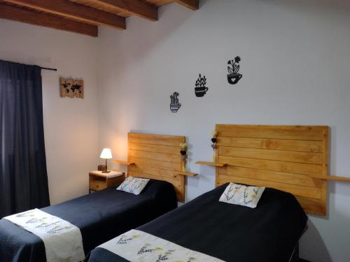 a bedroom with two beds and a wooden door at UCOGUESTHOUSE - Casa de Huéspedes in Vista Flores