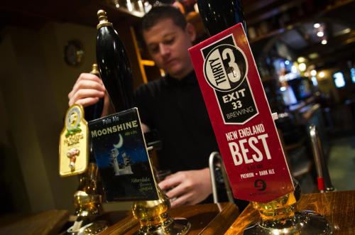 a man sitting at a bar with a bottle of beer at Norfolk Arms Hotel, Ringinglow in Sheffield