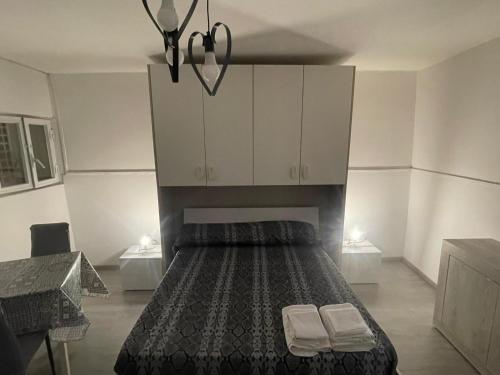 sypialnia z łóżkiem z białymi szafkami i 2 ręcznikami w obiekcie House Napoli w mieście Neapol