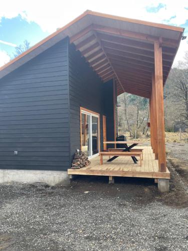 a black house with a bench on a deck at Malalcahuello Boske Suites in Malalcahuello