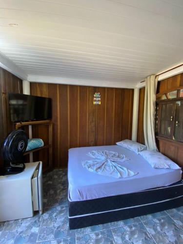 a bedroom with a bed and a flat screen tv at Pousada Margareth in Ilha do Mel