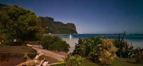 a view of a beach with the ocean and a mountain at Taria Camping in Te-Fare-Arii