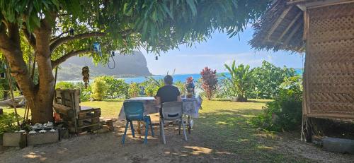 a man sitting at a table looking at the ocean at Taria Camping in Te-Fare-Arii