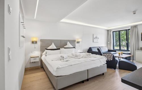 a white bedroom with a large bed and a living room at Baltic in Binz