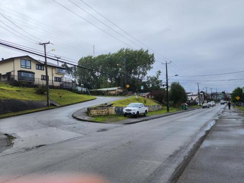 an empty street with cars parked on the road at Hostal Mirador Quellón in Quellón