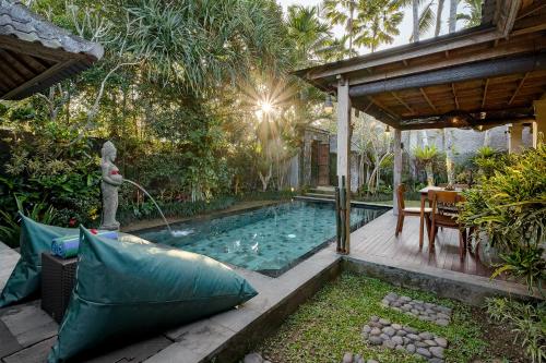 a swimming pool in a garden with a table and a house at Uddhara Ubud Villa in Ubud