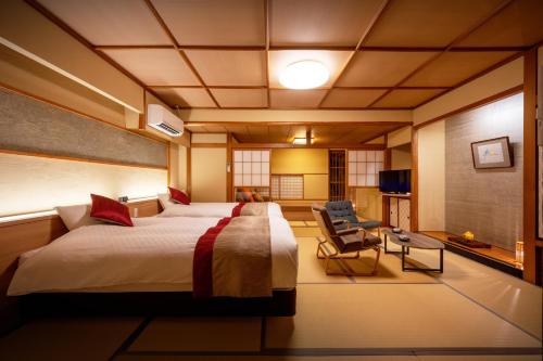 a hotel room with a large bed and a chair at Hohoemino Kuyufu Tsuruya in Tendo