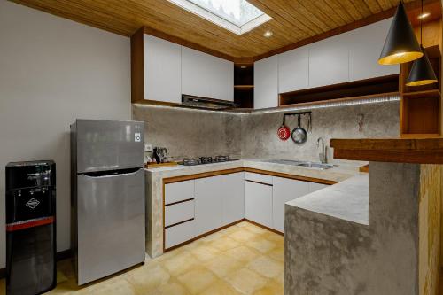 a kitchen with white cabinets and a silver refrigerator at Uddhara Ubud Villa in Ubud
